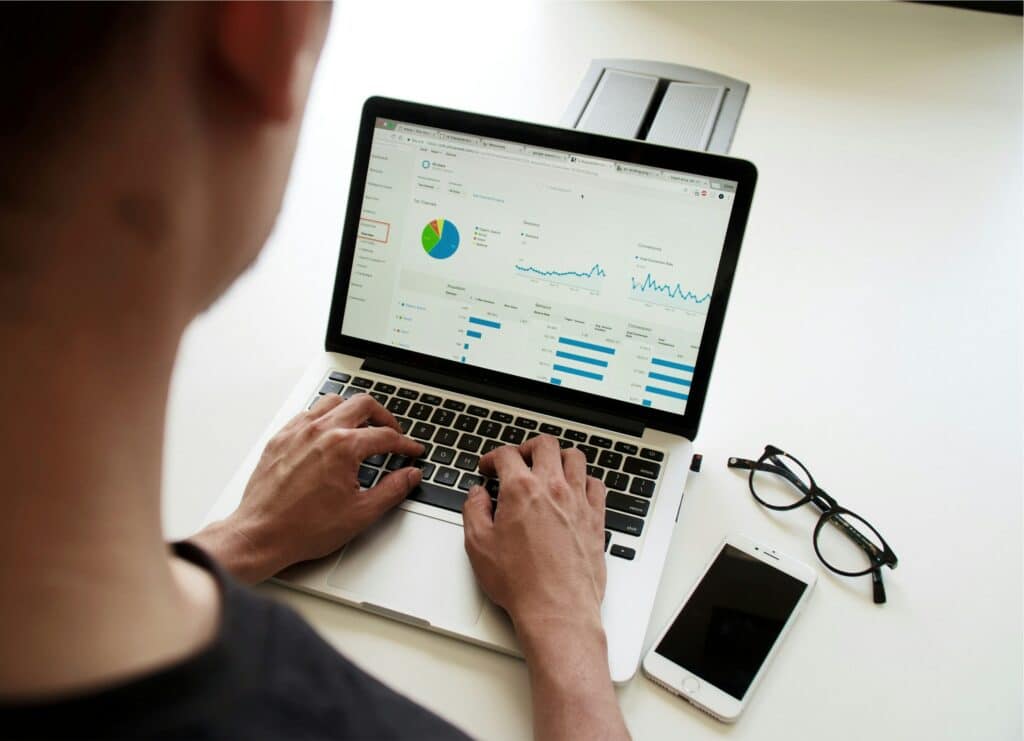 man working on a laptop with screen displaying graphs